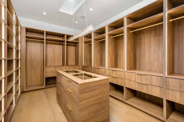 Warm wood veneer custom closet with a natural stone island countertop in a Bethesda MD home