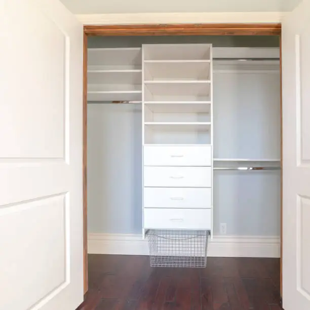 Custom reach-in closet with double hanging rods, pull-out drawers, and mirrored sliding doors in an Arlington VA bedroom
